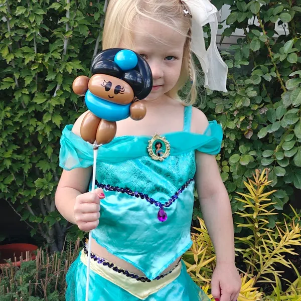 Girl in a princess costume holding a blue balloon character