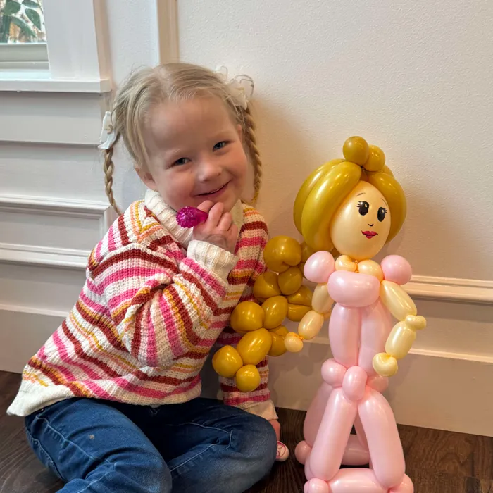 Girl posing with a pink and gold balloon princess character