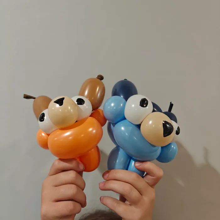 Kids holding orange and blue balloon puppy characters