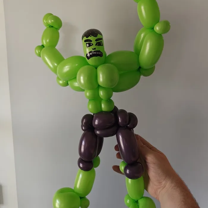 Green and purple balloon superhero character with raised arms